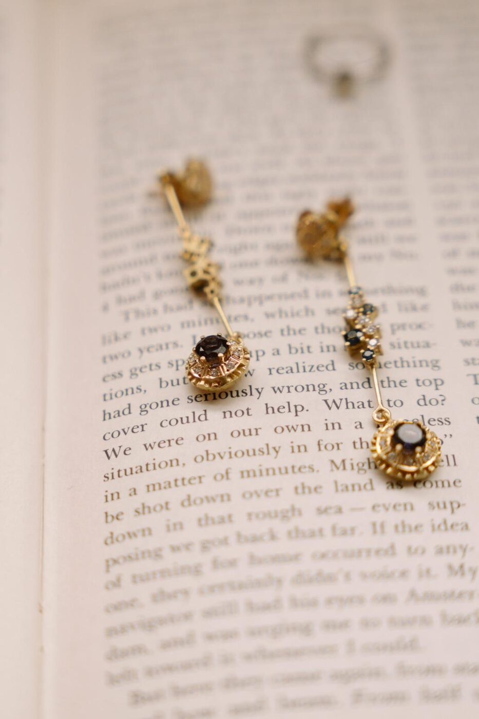 Pendientes largos de oro con zafiros sobre las páginas de un libro