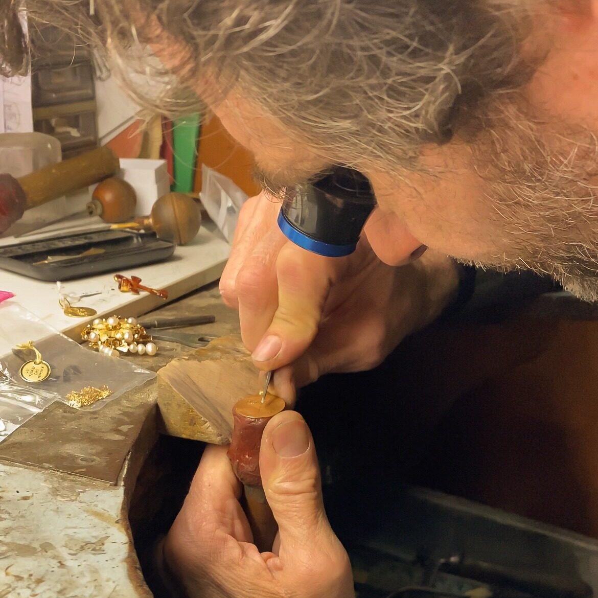 El joyero trabajando una pieza con la lupa en el taller